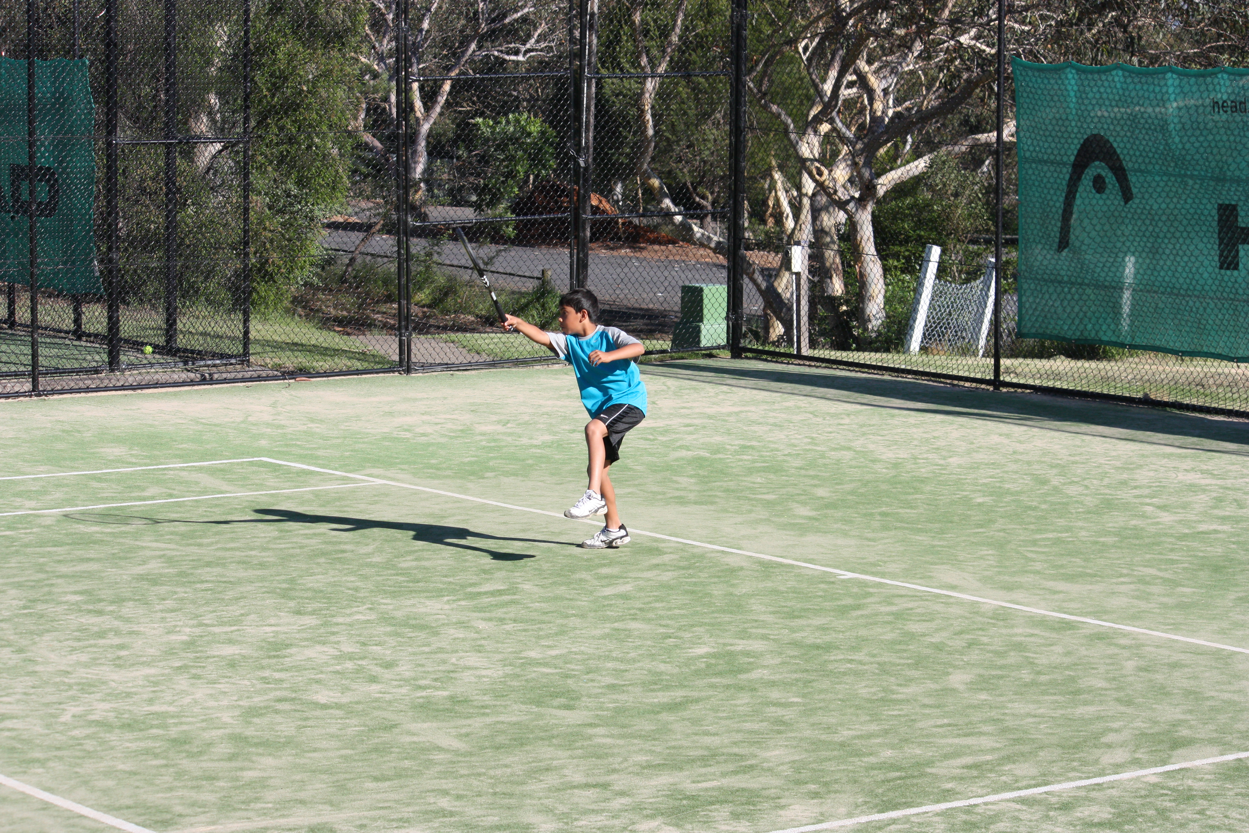 Young Rahul playing tennis, mid-shot on the tennis court