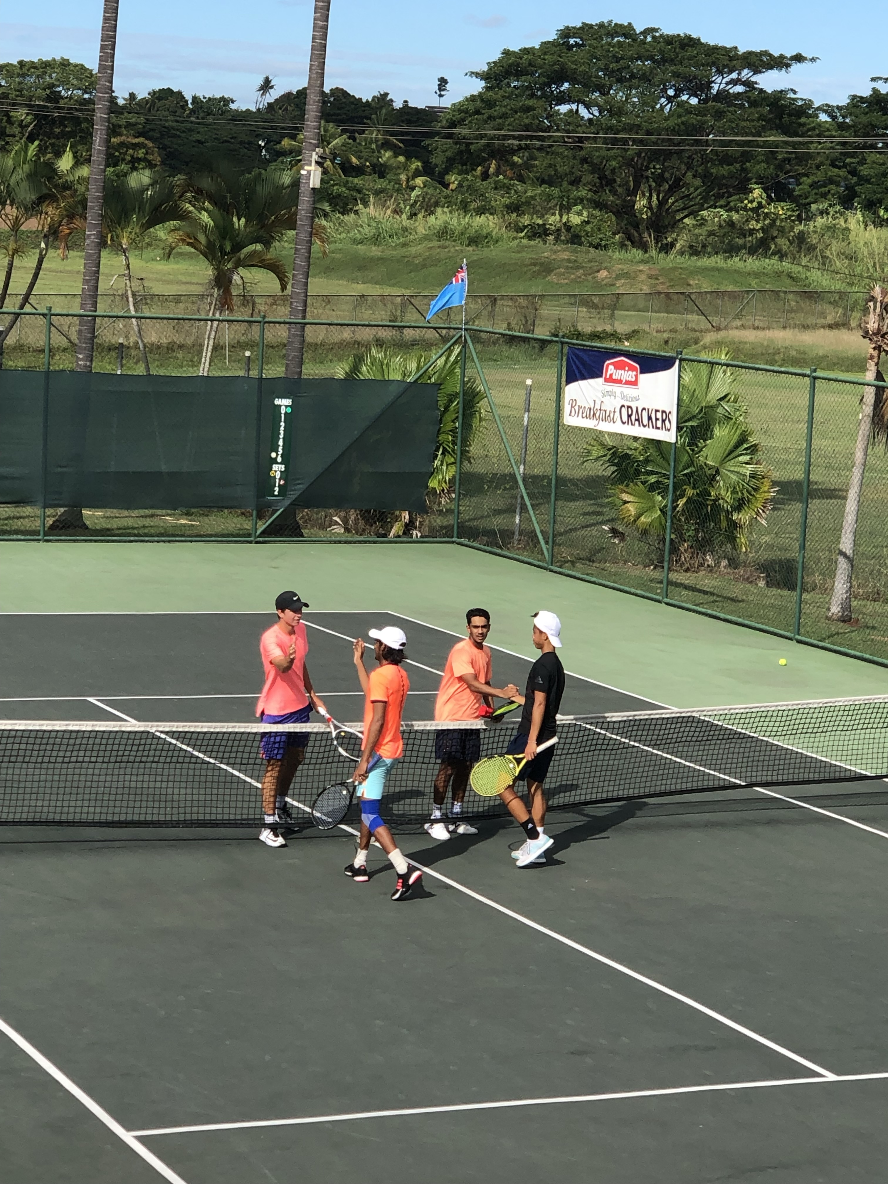 Playing tennis in Fiji with other players on court